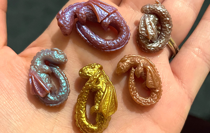 Final coloured polymer clay dragons in the palm of a hand