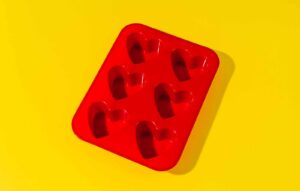Maintaining silicone moulds symbolised with a Red multiple heart shape silicone mould on a yellow background