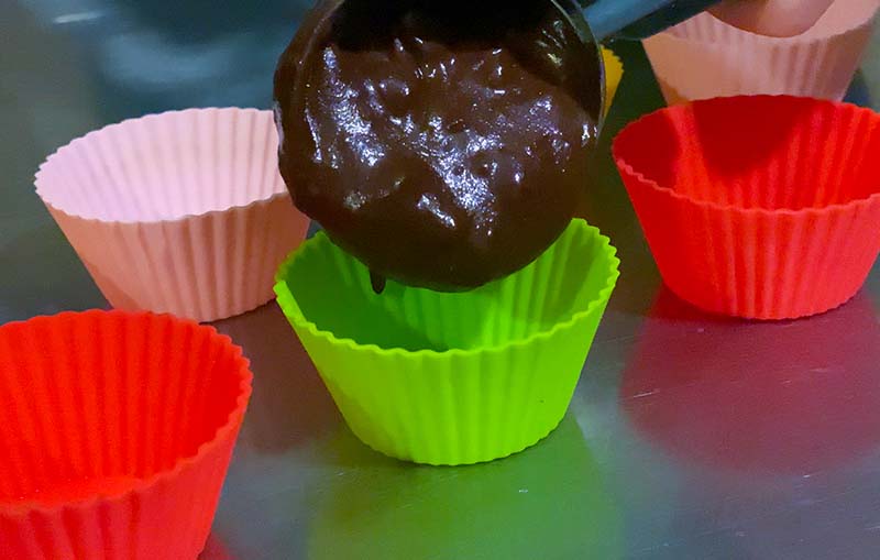 Pouring chocolate muffin batter into a silicone muffin case
