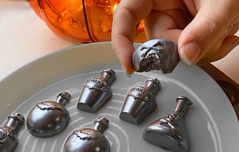 Halloween chocolate candy shaped as poison bottles. finished with a silver coating on a grey plate