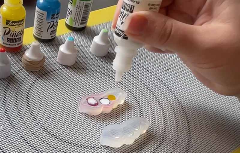Resin artist using white alcohol ink to fill a silicone mould