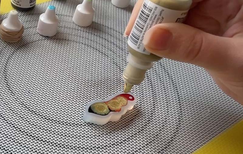 adding gold alcohol ink to resin in a silicone mould