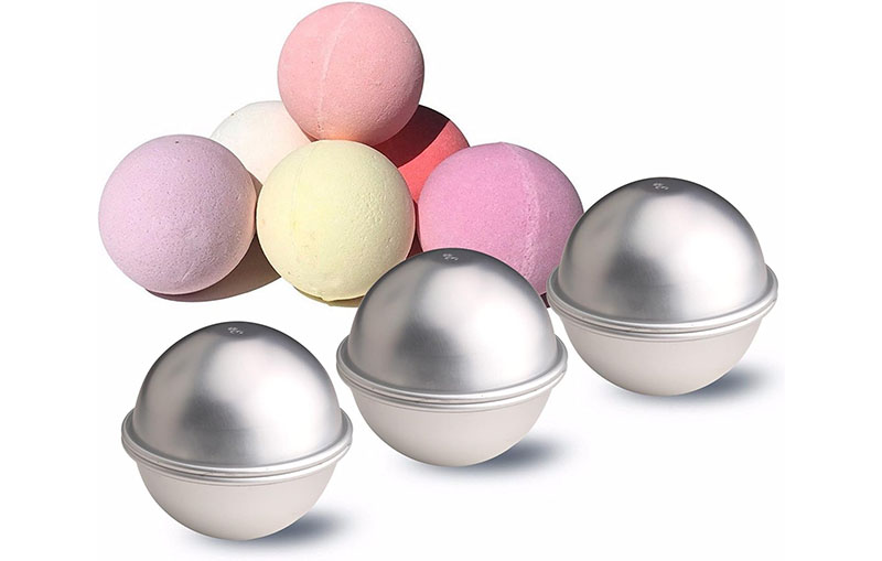 metal bah bomb molds with a variety of coloured bath bombs behind