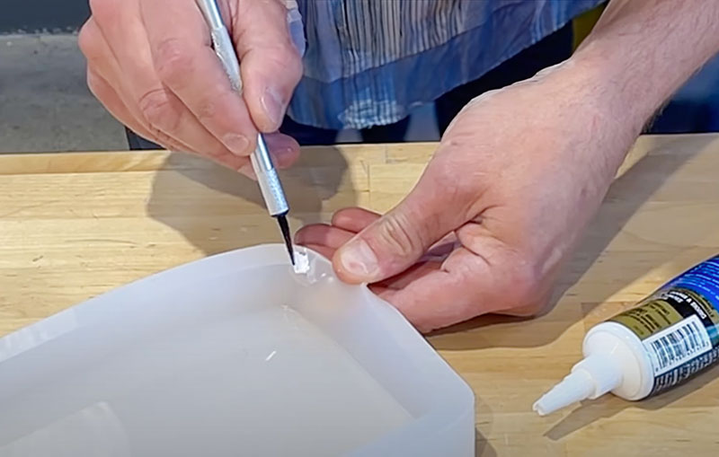 Man demonstrating how to repair a silicone mold with silicone sealant