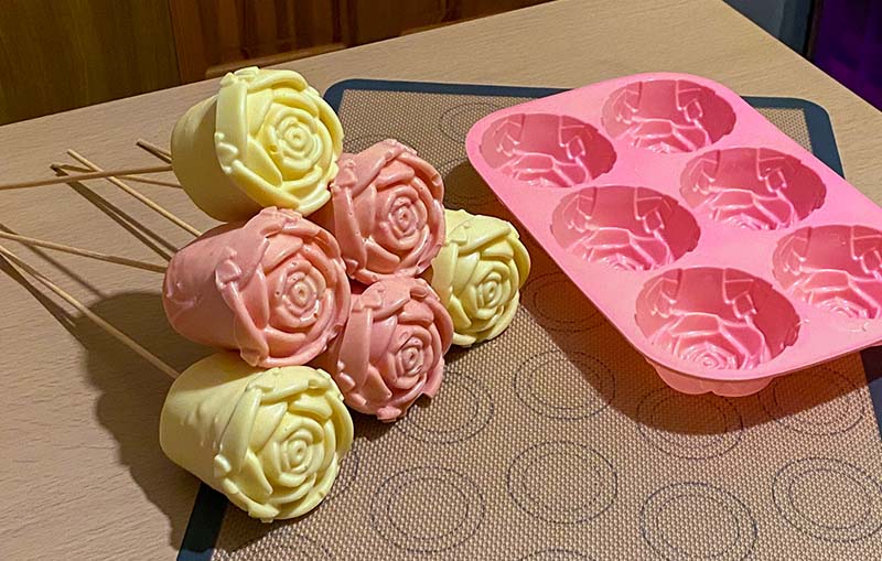 De-molded chocolate roses next to a pink rose silicone mold