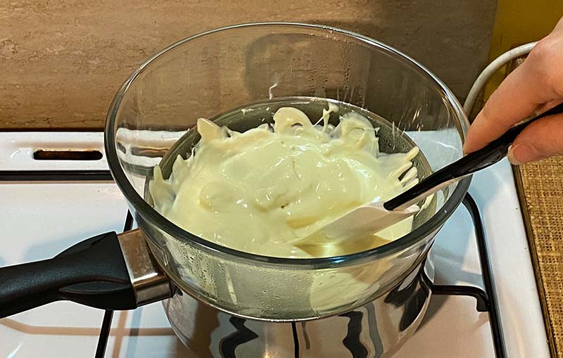 Melting white chocolate in a glass bowl and saucepan
