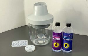 Resiners Airless Lite Bubble Remover with two bottles of resin and hardener, measuring tools, and mixing accessories on a professional resin artist's worktable.