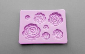 A pink silicone mold with 7 rose shaped cavities varying in different sizes and detail. How to make your own silicone mold