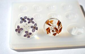 Two resin castings with embedded flowers on a silicone mold tray, showcasing the use of silicone molds for resin crafts
