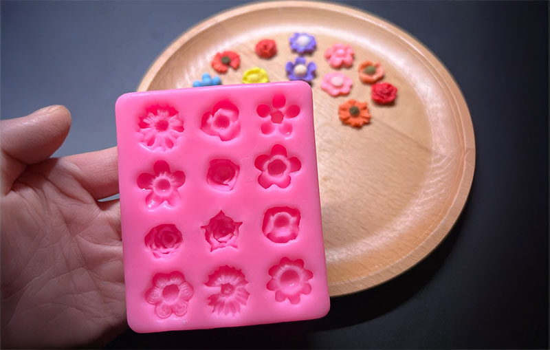 Clay for silicone molds - Pink floral-shaped silicone mold with colorful clay flower pieces.