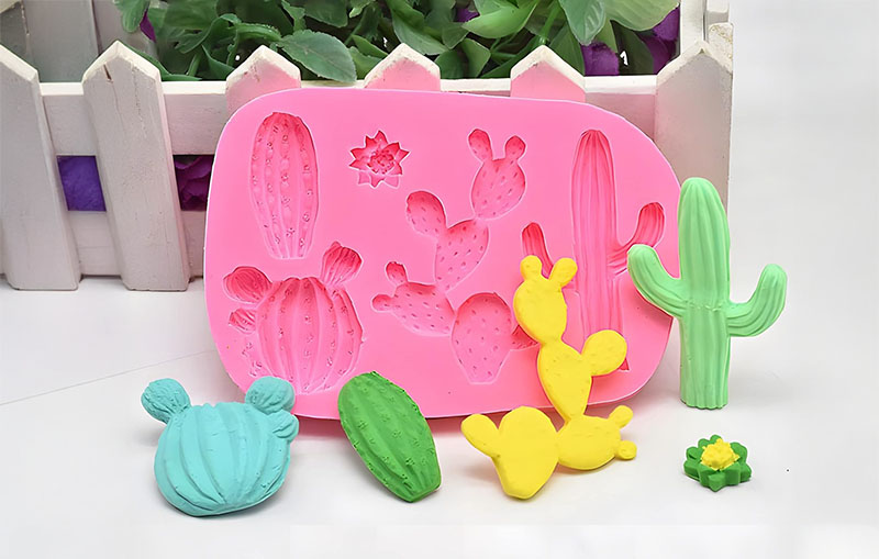 Clay for silicone molds - Pink silicone mold with cactus shapes and colorful clay cactus pieces.