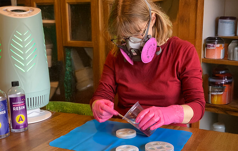 Crafter using the Resiners air purifier to improve air quality while working with resin.