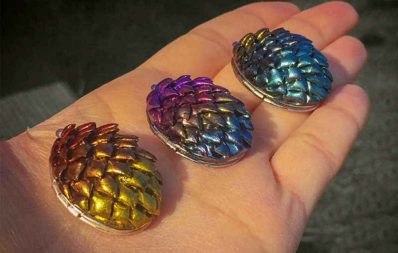Three hand crafted dragon egg Pendants made from polymer clay in the hand of the artist